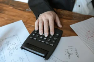 Immobilienmodell mit Taschenrechner und Bauplan zur Verkehrswertermittlung