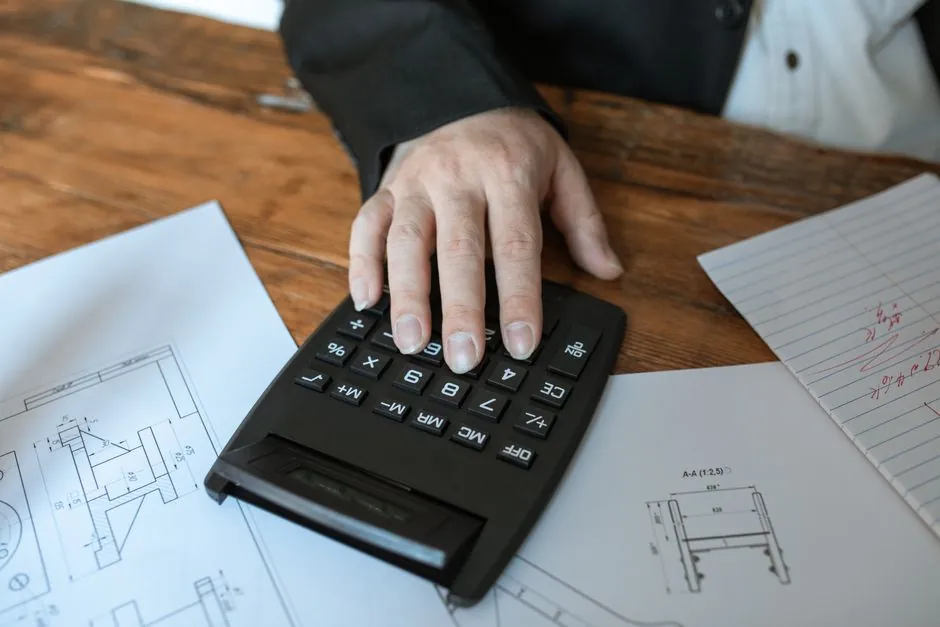 Immobilienmodell mit Taschenrechner und Bauplan zur Verkehrswertermittlung